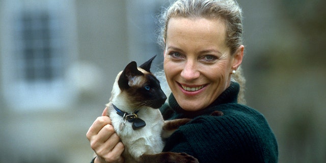 Princess Michael of Kent holds her pet Siamese cat in the gardens of her home, Nether Lypiatt Manor.