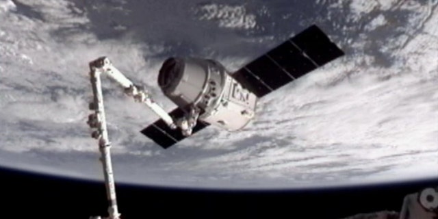 May 25, 2012: This image provided by NASA-TV shows the SpaceX Dragon commercial cargo craft, top, after Dragon was grappled by the Canadarm2 robotic arm and connected to the International Space Station.