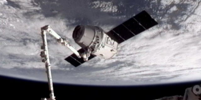 May 25, 2012: This image provided by NASA-TV shows the SpaceX Dragon commercial cargo craft, top, after Dragon was grappled by the Canadarm2 robotic arm and connected to the International Space Station.