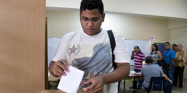 Puerto Rico resident Hector Feliciano votes during the U.S. territory's Democratic primary election at the Luis Llorens Torres Elementary School in San Juan, Puerto Rico, Sunday June 5, 2016 . Puerto Ricans frustrated by island's economic crisis are voting in the U.S. territory's Democratic presidential primary, as front-runner Hillary Clinton draws closer to securing the number of delegates needed to win her party's nomination. (AP Photo/Carlos Giusti)