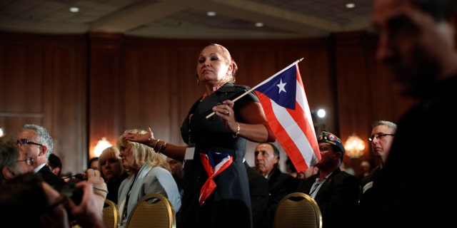 Elizabeth Cuevas-Neunder holds a Puerto Rican flag and asks Republican presidential candidate former House Speaker Newt Gingrich a question during the Hispanic Leadership Network conference at the Doral Golf Resort and Spa, Friday, Jan. 27, 2012, in Miami, Fla. Romney and Gingrich square off over immigration and other issues as they look to woo Hispanics a day after a feisty, final debate before Tuesdays Florida primary. (AP Photo/Matt Rourke)