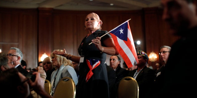 Elizabeth Cuevas-Neunder holds a Puerto Rican flag and asks Republican presidential candidate former House Speaker Newt Gingrich a question during the Hispanic Leadership Network conference at the Doral Golf Resort and Spa, Friday, Jan. 27, 2012, in Miami, Fla. Romney and Gingrich square off over immigration and other issues as they look to woo Hispanics a day after a feisty, final debate before Tuesdays Florida primary. (AP Photo/Matt Rourke)