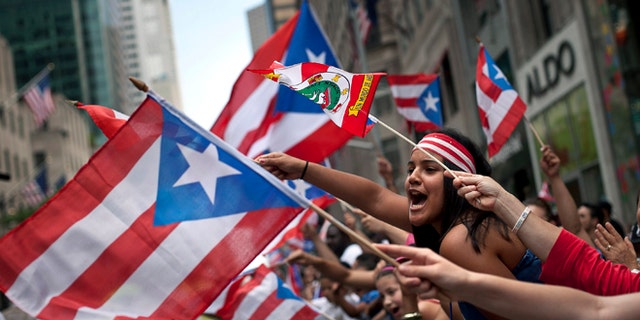 NEW YORK, NY - JUNE 10:  Revelers wave flags along Fifth Avenue during the Puerto Rican Day Parade on June 10, 2012 in New York City. The Puerto Rican Day Parade draws hundreds of thousands and was first celebrated in New York City in 1958. (Photo by Allison Joyce/Getty Images)