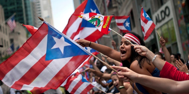 NEW YORK, NY - JUNE 10: Revelers wave flags along Fifth Avenue during the Puerto Rican Day Parade on June 10, 2012 in New York City. The Puerto Rican Day Parade draws hundreds of thousands and was first celebrated in New York City in 1958. (Photo by Allison Joyce/Getty Images)