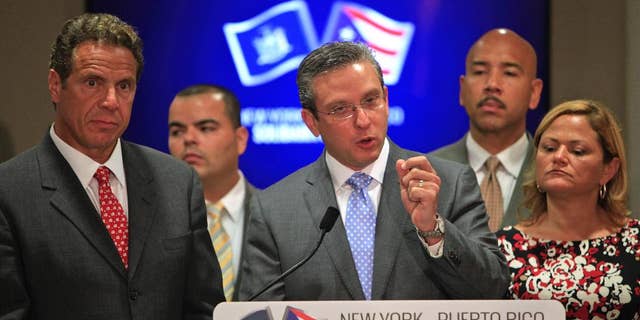 New York Gov. Andrew Cuomo, left, stands next to Puerto Rico Gov. Alejandro Garcia Padilla, during a joint news conference in San Juan, Puerto Rico, Tuesday, Sept. 8, 2015. Cuomo and a delegation of top state officials met with Puerto Rico's Gov. Alejandro Garcia Padilla, pictured left, on Tuesday to develop what he called a historic partnership with the U.S. territory to help it emerge from a deepening economic crisis. (AP Photo/Ricardo Arduengo)