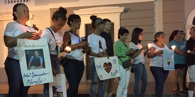 People gather with posters and candles in Ponce, Puerto Rico, Monday, June 13, 2016, during a vigil for the victims of Sunday's Orlando shootings at a gay nightclub in Florida. At least 5 of the 49 victims were from Ponce, the second largest city on Puerto Rico's southern coast. (AP Photo/Danica Coto)