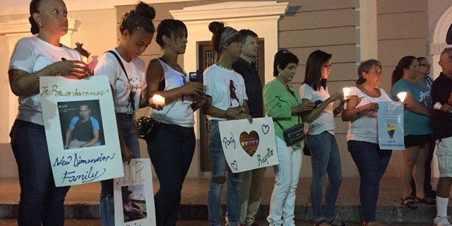 People gather with posters and candles in Ponce, Puerto Rico, Monday, June 13, 2016, during a vigil for the victims of Sunday's Orlando shootings at a gay nightclub in Florida. At least 5 of the 49 victims were from Ponce, the second largest city on Puerto Rico's southern coast. (AP Photo/Danica Coto)