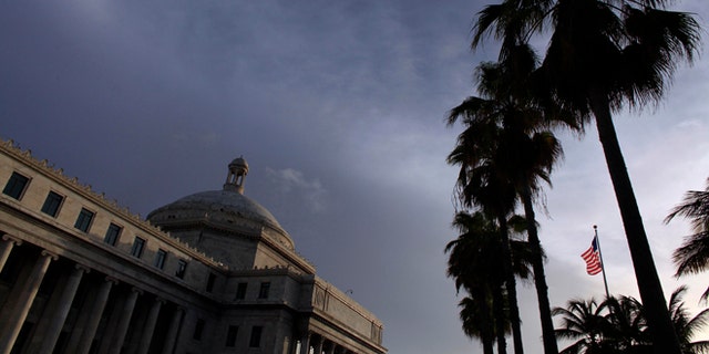 In this July 29, 2015 photo, the U.S. flag flies in front of Puerto Ricos Capitol in San Juan, Puerto Rico. A Puerto Rico senator has filed a resolution that would reassign $94 million to the island's Government Development Bank so it can make a bond payment that the U.S. territory missed on Aug. 1. The non-payment prompted Oppenheimer Funds Inc. and Franklin Advisers Inc. to issue a letter addressed to Puerto Rico's Government Development Bank demanding that bondholders be paid. (AP Photo/Ricardo Arduengo)