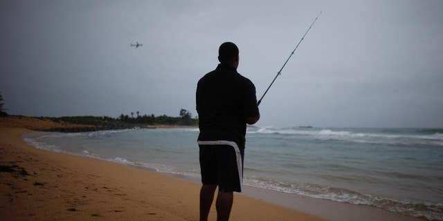 A man fishes as a cluster of storms passes through the area, in San Juan, Puerto Rico, Friday, Aug. 22, 2014. The National Weather Service in San Juan said the region could be hit with up to 6 inches (15 centimeters) of rain and wind gusts of 35 mph (56 kph). (AP Photo/Ricardo Arduengo)