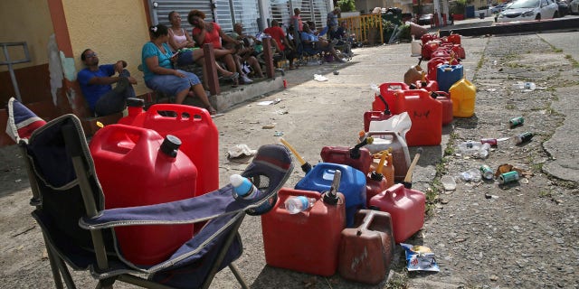 Residents line up gas cans as they wait for a gas truck to service an empty gas station, in the aftermath of Hurricane Maria in Loiza, Puerto Rico.