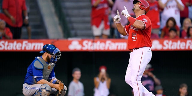 Los Angeles Angels' Albert Pujols, right, points to the sky as he scores after hitting a solo home run as Toronto Blue Jays catcher Russell Martin kneels at the plate during the second inning of a baseball game, Saturday, Sept. 17, 2016, in Anaheim, Calif. (AP Photo/Mark J. Terrill)