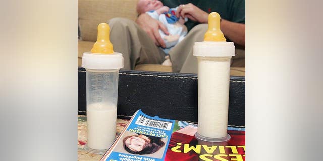 In this Oct. 12, 2005 file photo, a father holds his baby as bottles of milk are seen in the foreground in Alpharetta, Ga.