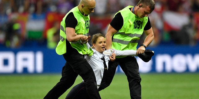 Stewards pull a woman off the pitch after she stormed onto the field and interrupted the final match between France and Croatia at the 2018 soccer World Cup in the Luzhniki Stadium.