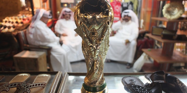 DOHA, QATAR - OCTOBER 24: Arab men sit at a shoemaker's stall with a replica of the FIFA World Cup trophy in the Souq Waqif traditional market on October 24, 2011 in Doha, Qatar. Qatar will host the 2022 FIFA World Cup football competition and is slated to tackle a variety of infrastructure projects, including the construction of new stadiums. (Photo by Sean Gallup/Getty Images)