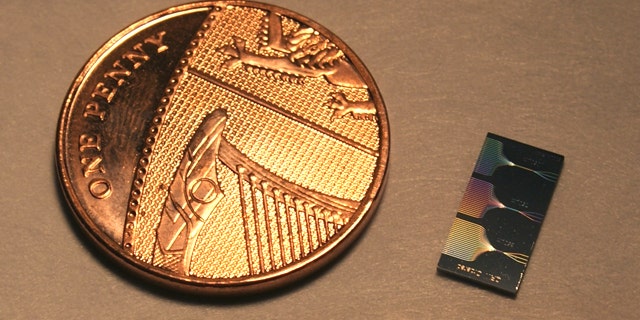 This is the photonic chip next to a UK penny. The chip contains micrometer and sub-micrometer features and guide light using a network of waveguides. The output of this network can be seen on the surface of the chip.