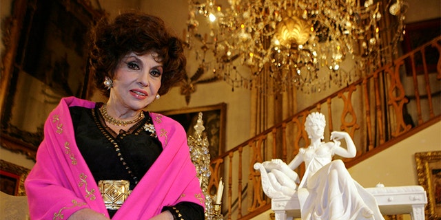 Italian film icon Gina Lollobrigida poses near one of her marble sculptures in her villa in southern Rome December 7, 2006. Lollobrigida vowed on Thursday to make the media pay for ruining her plans to marry Javier Rigau, a Spaniard 34 years her junior. In an interview with Reuters after she arrived in Rome from Philadelphia, the 79-year-old film star said the couple had called off their wedding plans after Rigau was worn down by "endless attacks, slander and violence" from the media. REUTERS/Chris Helgren (ITALY) - GM1DUCNMRLAA