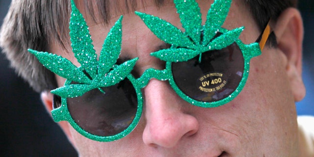 A man wears novelty sunglasses adorned with artificial marijuana leaves as he sells them across the street from a pro-marijuana rally at the University of Colorado in Boulder, Colorado April 20, 2012. (REUTERS/Rick Wilking)