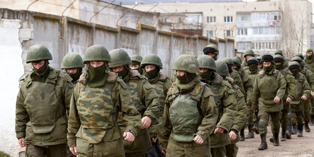 March 14, 2014 - Armed men, believed to be Russian servicemen, walk outside a Ukrainian military base in Perevalnoye, near the Crimean city of Simferopol. A Russian warship unloaded trucks, troops and at least one armored personnel carrier at a bay near Sevastopol in Crimea on Friday morning, as Moscow continued to build up its forces on the Ukrainian peninsula. REUTERS