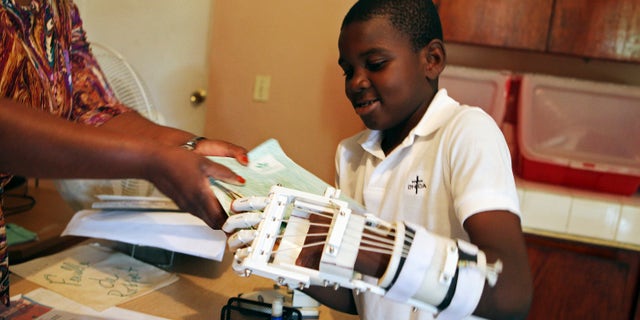 Handicapped Haitian boy Stevenson Joseph learns to use a 3D-printed prosthetic hand at the orphanage where he lives in Santo, near Port-au-Prince, April 28, 2014. (REUTERS/Marie Arago)