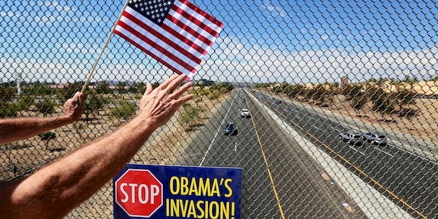 An anti-immigration protester holds a flag and waves to motorists on a highway overpass on Murrieta Hot Springs Blvd in Murrieta, California July 19, 2014. U.S. President Barack Obama will meet with the leaders of Honduras, Guatemala and El Salvador next week to discuss cooperation on the influx of child migrants from Central America into the United States, senior administration officials said on Friday. REUTERS/Sandy Huffaker (UNITED STATES - Tags: SOCIETY IMMIGRATION CIVIL UNREST POLITICS) - RTR3ZD18