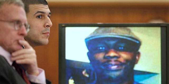 Former New England Patriots football player Aaron Hernandez listens during his trial as defense attorney Charles Rankin (L), looks on while an image of Odin Lloyd is displayed on a monitor in Fall River, Massachusetts, January 29, 2015. Hernandez is accused of murdering semi-professional football player Odin Lloyd.