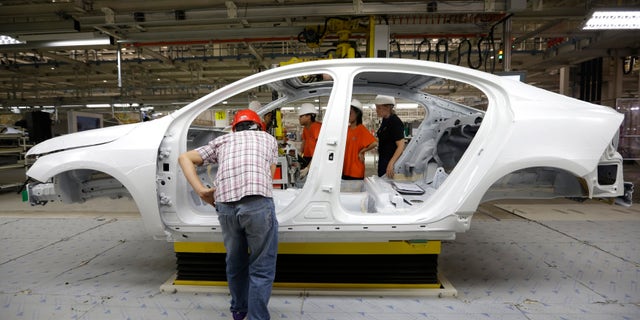 Workers prepare to assemble parts of a Volvo car at an assembly line of the new Volvo automobile manufacturing plant in Chengdu, Sichuan province, June 5, 2013. Chinese-owned Swedish automaker Volvo Car Corp expects to be selling 200,000 cars a year in China by 2018, a senior executive said, two years ahead of its latest target and as a new assembly plant gears up for full production later this year. REUTERS/Jason Lee (CHINA - Tags: TRANSPORT BUSINESS EMPLOYMENT) - RTX10CA4