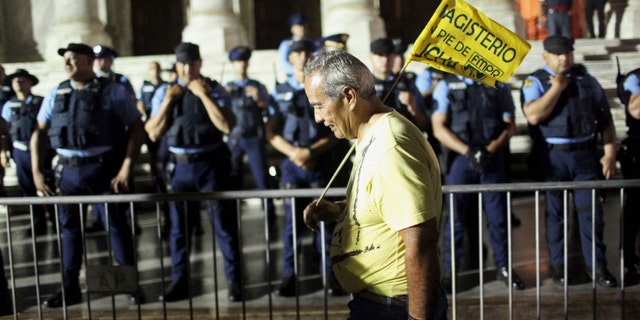 A schoolteacher demonstrates outside of the Capitol building as the Lower House of Congress voted to approve modifications to the Teacher's Pension System in San Juan, December 21, 2013. Puerto Rico, with an economy in or near recession for the last eight years, has chronic budget shortfalls and has spawned worry among investors in the $3.7 trillion municipal debt market, where its bond prices have plunged this year. Picture taken December 21, 2013. REUTERS/Alvin Baez (PUERTO RICO - Tags: EDUCATION POLITICS BUSINESS EMPLOYMENT) - RTX16RDT
