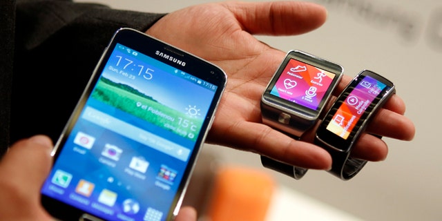 New Samsung Galaxy S5 smartphone (L), Gear 2 smartwatch (C) and Gear Fit fitness band are displayed at the Mobile World Congress in Barcelona.