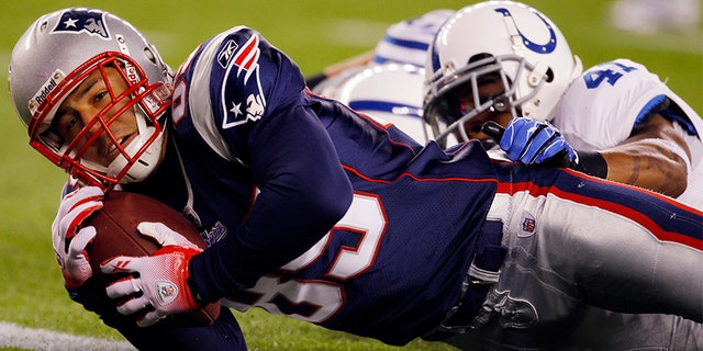 New England Patriots tight end Aaron Hernandez (L) scores a touchdown as he is tackled by Indianapolis Colts safety Antoine Bethea in the second quarter of their NFL football game in Foxborough, Massachusetts November 21, 2010.