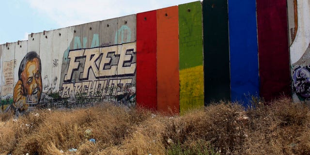 Monday, June 29, 2015: Palestinian artist Khaled Jarrar shows his painting of a rainbow flag on six slabs of the West Bank separation barrier in the West Bank city of Ramallah.