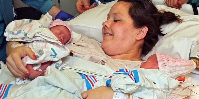 FILE - In this May 9, 2014 photo, Sarah Thistlethwaite holds her twin daughters, Jenna and Jillian, after her delivery of the monoamniotic twin girls at Akron General Hospital in Akron, Ohio. The rare twins, who gained international attention after they were photographed holding hands moments after their birth last month, are home in time for Father's Day. (AP Photo/Akron Beacon Journal, Ed Suba Jr.File)
