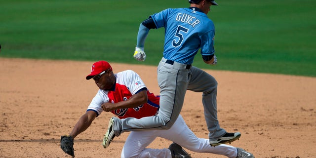 Cuba's Alexander Malleta dives for first base, too late to stop Tampa Bay Rays' Brandon Guyer during a game between the Rays and Cuba's national baseball team in Havana, Cuba, Tuesday, March 22, 2016. President Barack Obama and his family watched the game with Cuba's President Raul Castro, then left early for the airport where the first family departed for Argentina. Tampa Bay defeated Cuba 4-1. (AP Photo/Rebecca Blackwell)