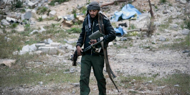 April 23, 2011: A Libyan rebel fighter carries a heavy machine gun in the besieged city of Misrata, Libya.