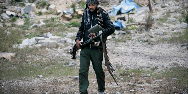 April 23, 2011: A Libyan rebel fighter carries a heavy machine gun in the besieged city of Misrata, Libya.