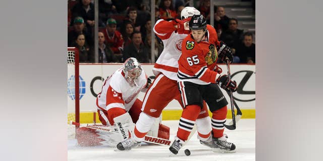 Chicago Blackhawks' Andrew Shaw (65), right, controls the puck against Detroit Red Wings' Jonathan Ericsson, center, and goalie Jimmy Howard (35) during the second period of an NHL hockey game in Chicago, Sunday, March 16, 2014. (AP Photo/Nam Y. Huh)