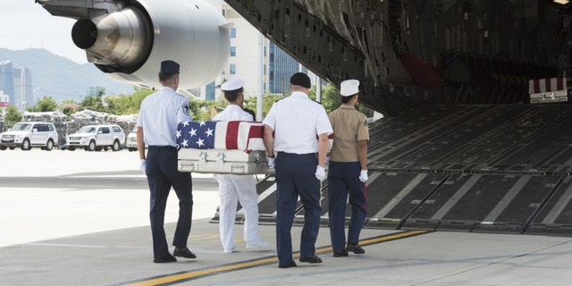 U.S. service members, assigned to the Defense POW/MIA Accounting Agency (DPAA), carry a transfer case.