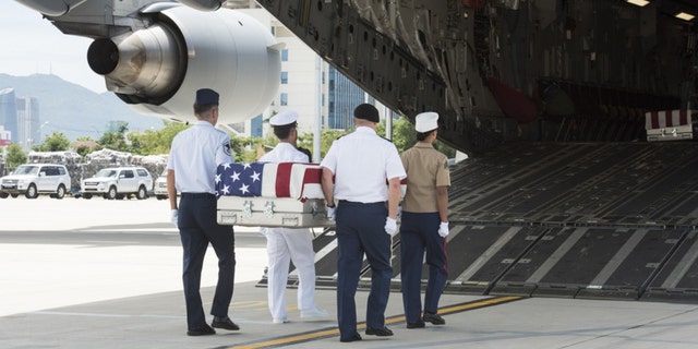 U.S. service members, assigned to the Defense POW/MIA Accounting Agency (DPAA), carry a transfer case.