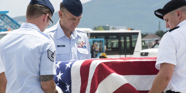 U.S. service members assigned to the Defense POW/MIA Accounting Agency (DPAA), drape a transfer case with the American flag during a repatriation ceremony, Da Nang, Socialist Republic of Vietnam, July 8, 2018.