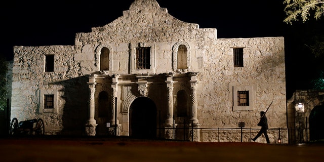 FILE - In this March 6, 2013, file photo, John Potter, a member of the San Antonio Living History Association, patrols the Alamo in San Antonio, during a pre-dawn memorial ceremony to remember the 1836 Battle of the Alamo and those who fell on both sides.