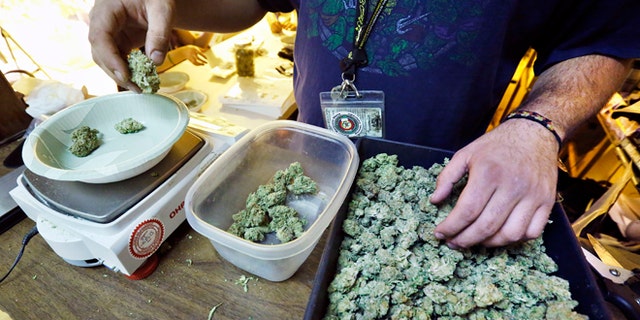 An employee weighs portions of retail marijuana to be packaged and sold at 3D Cannabis Center in Denver.