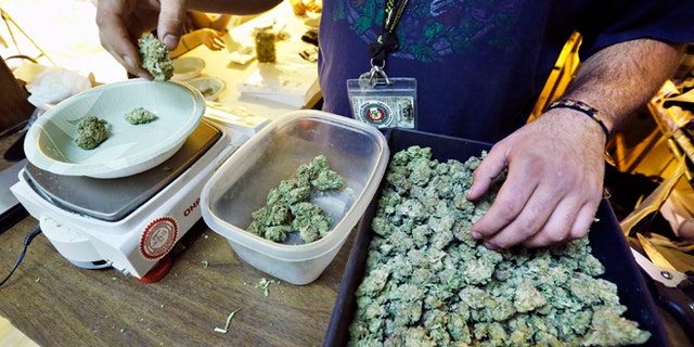 An employee weighs portions of retail marijuana to be packaged and sold at 3D Cannabis Center in Denver.