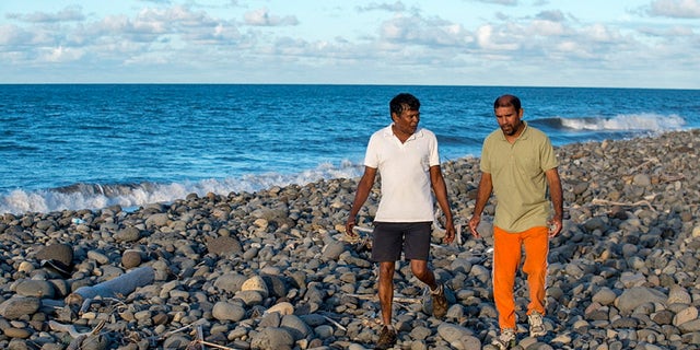July 30, 2015 - Johnny Begue (R), who found plane debris Wednesday on this beach in Saint-Andre, on the French Indian Ocean island of La Reunion, walks with his friend Andre Tevane. Begue found a flaperon, which help pilots control an aircraft in flight, on Wednesday. French authorities are studying the piece to determine whether it came from Malaysia Airlines Flight MH370.