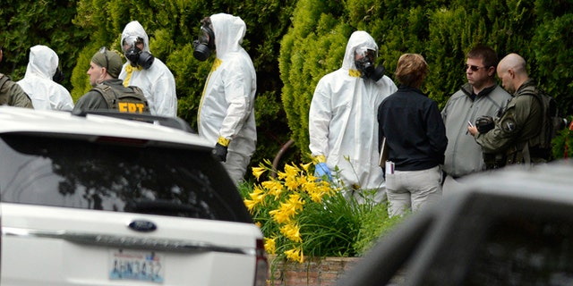 May 18, 2013: During the execution of a search warrant, members of the Joint Federal Haz-Mat Team, FBI, and local law enforcement gather in front of the Osmun Apartments near the intersection of First Avenue and Oak Street in Browne's Addition on Saturday in Spokane, Wash. The search warrant is in connection with ricin-laced letters intercepted at a Post Office facility in Spokane earlier in the week.
