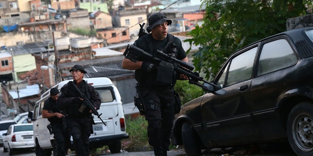 RIO DE JANEIRO, BRAZIL - MAY 13:  Officers from the CORE police special forces patrol during an operation to search for fugitives in the Complexo do Alemao pacified community, or 'favela' on May 13, 2014 in Rio de Janeiro, Brazil. Ahead of the 2014 FIFA World Cup, Rio has seen an uptick in violence in its pacified slums. A total of around 1.6 million Rio residents live in shantytowns, many of which are controlled by drug traffickers.  (Photo by Mario Tama/Getty Images)