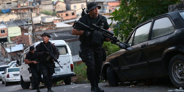 RIO DE JANEIRO, BRAZIL - MAY 13: Officers from the CORE police special forces patrol during an operation to search for fugitives in the Complexo do Alemao pacified community, or 'favela' on May 13, 2014 in Rio de Janeiro, Brazil. Ahead of the 2014 FIFA World Cup, Rio has seen an uptick in violence in its pacified slums. A total of around 1.6 million Rio residents live in shantytowns, many of which are controlled by drug traffickers. (Photo by Mario Tama/Getty Images)