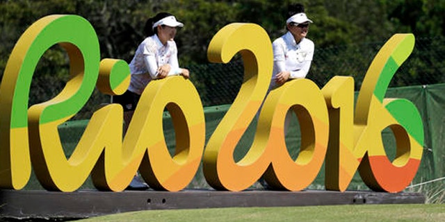 FILE - In this Aug.16, 2016 file photo, Kelly Tan, left, and Michelle Koh both of Malaysia, pose for a photo with the Rio 2016 logo on the 16th hole during a practice round for the women's golf event at the 2016 Summer Olympics in Rio de Janeiro, Brazil. The Rio Olympics could leave behind at least one unexpected legacy _ a new home for the consular office of the United States. The headquarters of the Rio de Janeiro Olympic organizing committee in central Rio will be abandoned in the next few weeks with staff moving to smaller quarters in downtown Rio. (AP Photo/Chris Carlson, File)