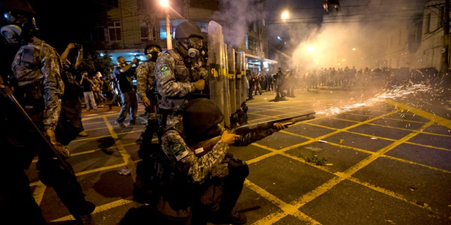 FILE - In this June 30, 2013 file photo, military police fire tear gas at protestors near Maracana stadium as Brazil and Spain play the final Confederations Cup soccer match in Rio de Janeiro, Brazil. Brazil has created a special riot force to help police control demonstrations expected during the 2014 World Cup, and authorities say they will not let protesters get too close to the stadiums. (AP Photo/Silvia Izquierdo, File)