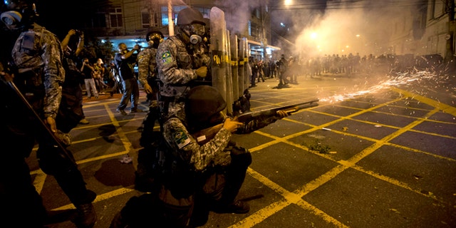 FILE - In this June 30, 2013 file photo, military police fire tear gas at protestors near Maracana stadium as Brazil and Spain play the final Confederations Cup soccer match in Rio de Janeiro, Brazil. Brazil has created a special riot force to help police control demonstrations expected during the 2014 World Cup, and authorities say they will not let protesters get too close to the stadiums. (AP Photo/Silvia Izquierdo, File)