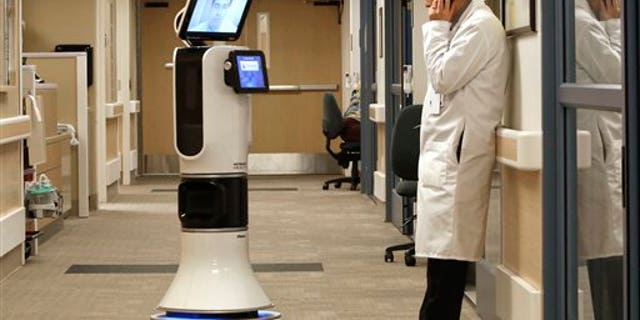 In this photo taken Wednesday, Nov. 6, 2013 Dr. Alan Shatzel, medical director of the Mercy Telehealth Network, is displayed on the monitor RP-VITA robot as he waits to confer with Dr. Alex Nee at Mercy San Juan Hospital in Carmichael, Calif. The robots enable physicians to have "beam" themselves into hospitals to diagnose patients and offer medical advice during emergencies. (AP Photo/Rich Pedroncelli)