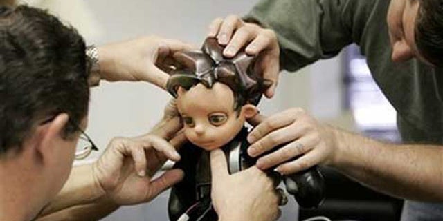Jason Mitchell, left, and Joshua Varner, right, make adjustments to Zeno, a robot boy creation by Hanson Robotics. Japanese researchers hope a similar robot will help boost sagging birth rates.